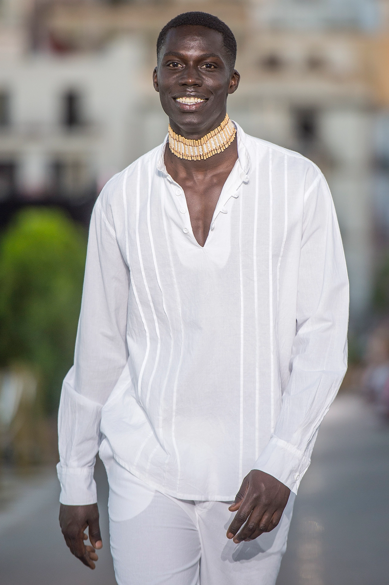 Modelo masculino con camisa blanca de lino con pliegues y collar dorado